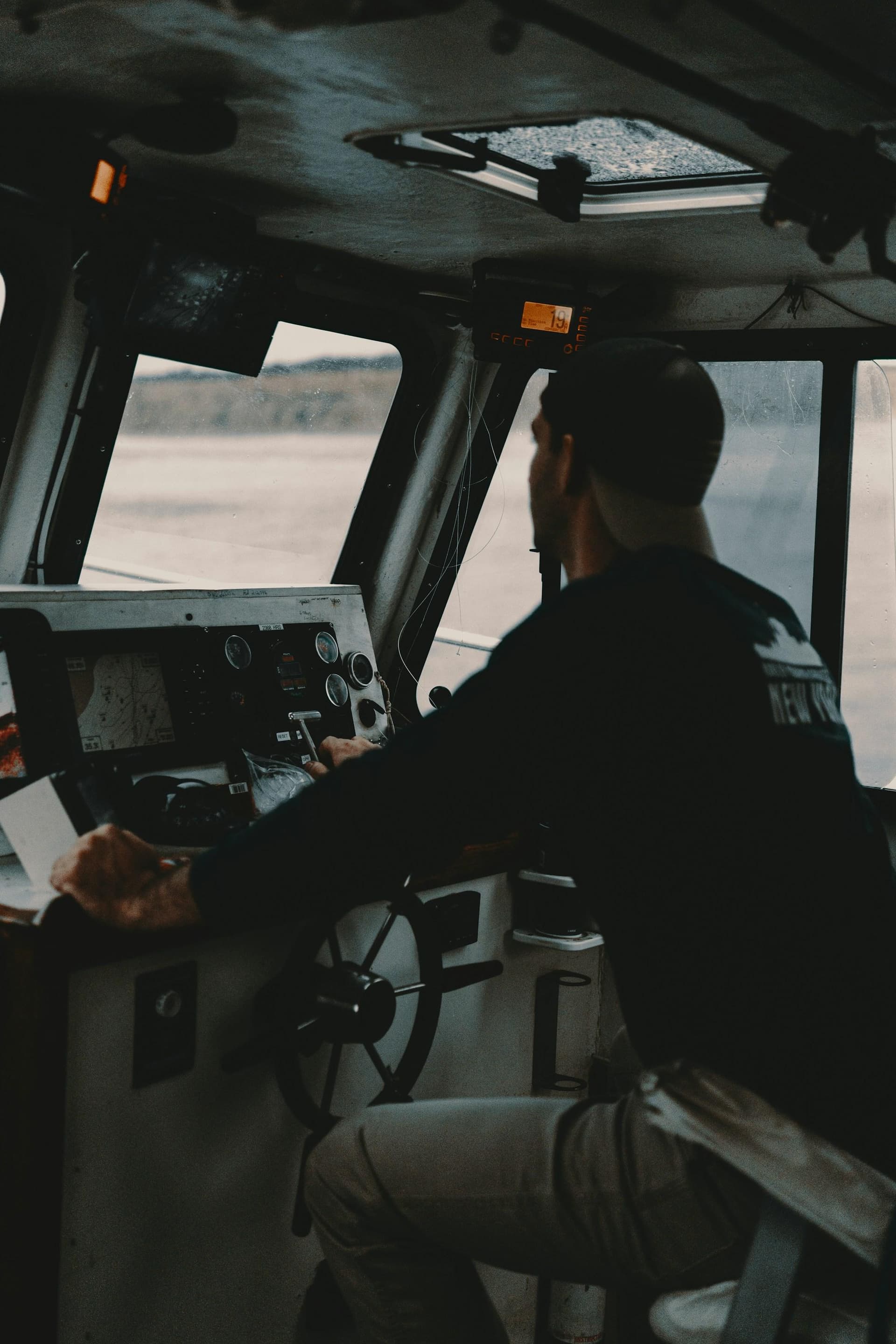 A captain at the wheel of a passenger boat, navigating from the helm