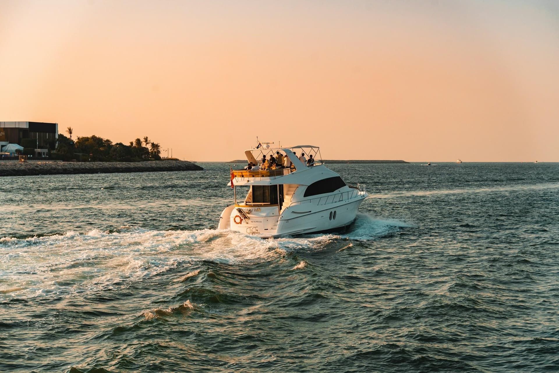 A white yacht cruising across open water at golden hour